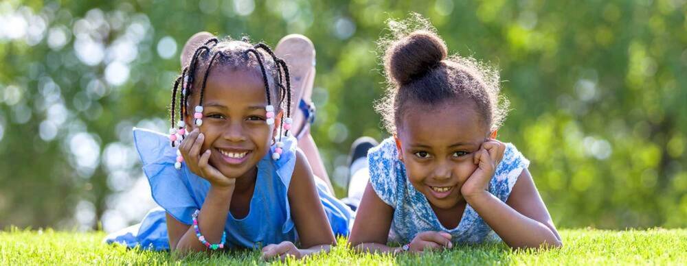 Two girls laying in the grass smiling.