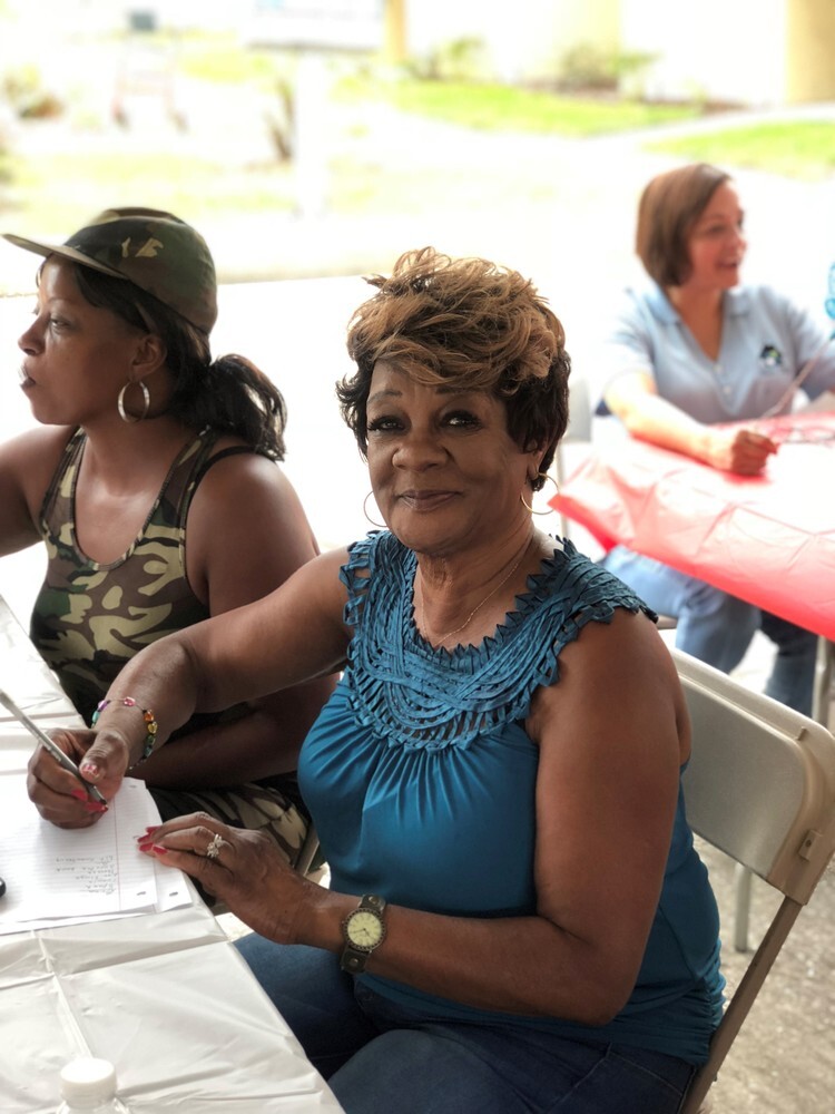 Woman smiling at a table with a pencil filling out a form. 